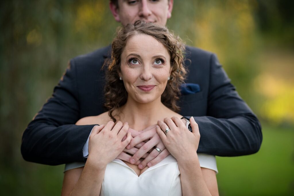 bride smiles looking up at her groom, who is standing behind her