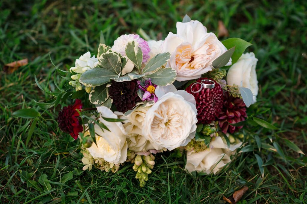 bride's bouquet of cream, red and light pink flowers on the grass at the stonington lighthouse museum