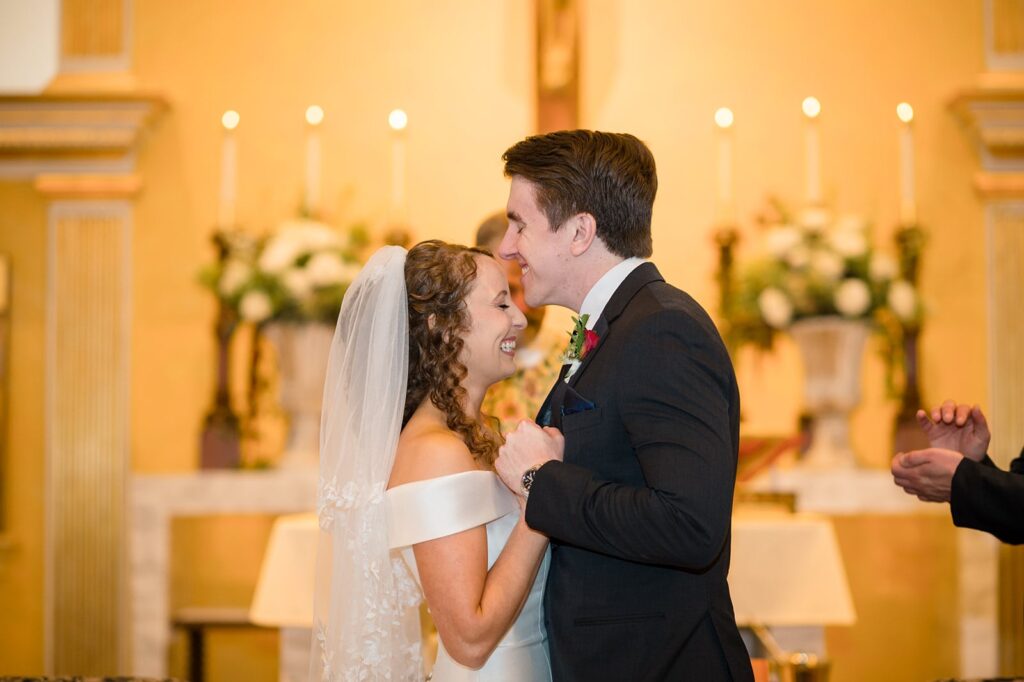 bride and groom smile and their faces touch during their wedding mass