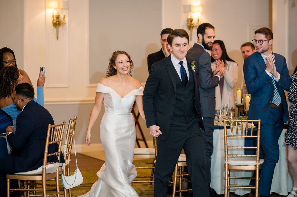 bride and groom walk into their wedding reception holding hands at the hounds in stonington ct